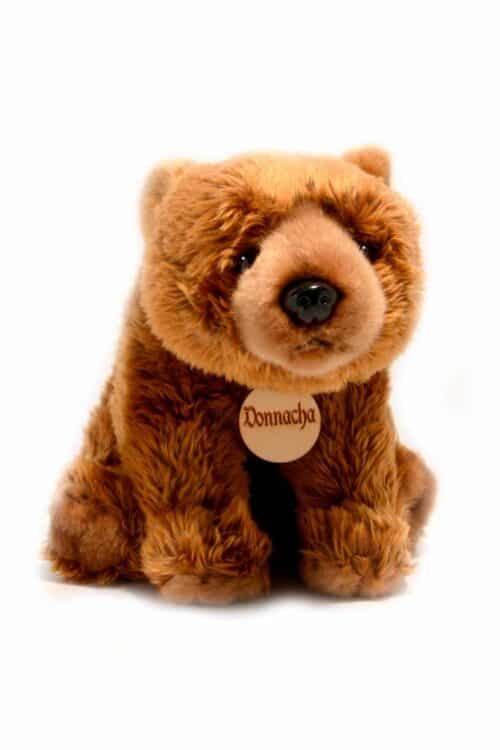 Wild Ireland - A plush brown bear sits on a white background. It has soft, fluffy fur and a small black nose. A round wooden tag on its neck reads Donnacha.