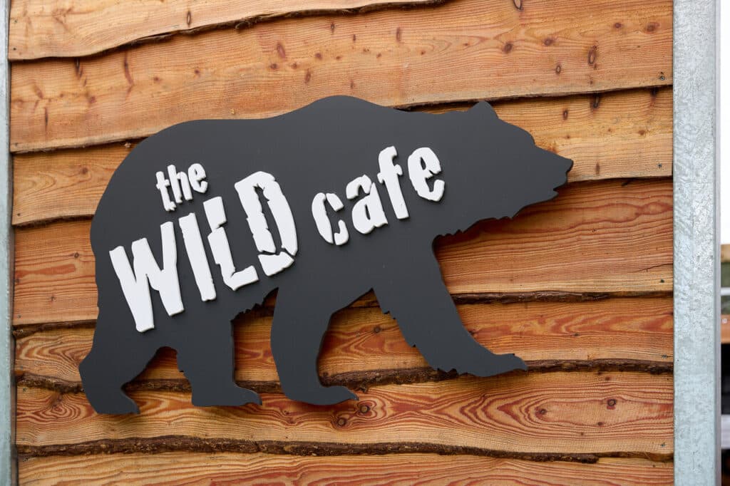 Wild Ireland - Sign for The Wild Cafe in the shape of a bear silhouette. The silhouette is black with white lettering and is mounted on a wooden wall with horizontal planks.