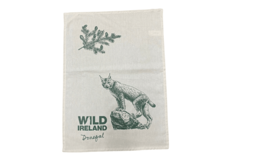 Wild Ireland - The Tea Towel Lynx is a linen tea towel with a printed design of a lynx on a rock, along with a branch and leaves. The text Wild Ireland Donegal appears in dark green.