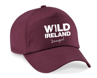 Wild Ireland - A bright pink baseball cap with Wild Ireland Donegal in white on the front, featuring rugged Wild letters. The cap includes a curved brim and a top button.