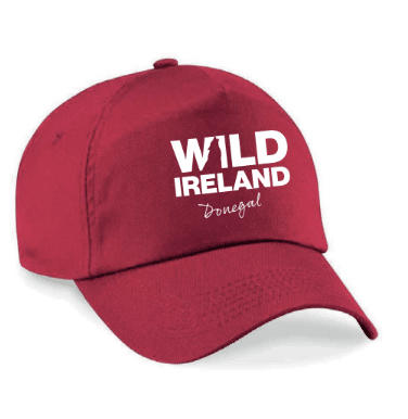 Wild Ireland - A bright pink baseball cap with white embroidered text saying WILD IRELAND Donegal, featuring a silhouette map of Ireland. It includes a curved brim and visible panel stitching.
